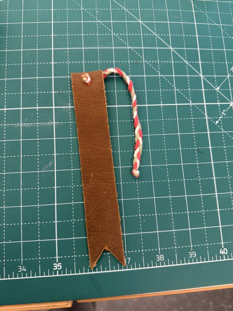 leather bookmark made from 1" wide leather, with a braided tassle of green, white, and red yarn
